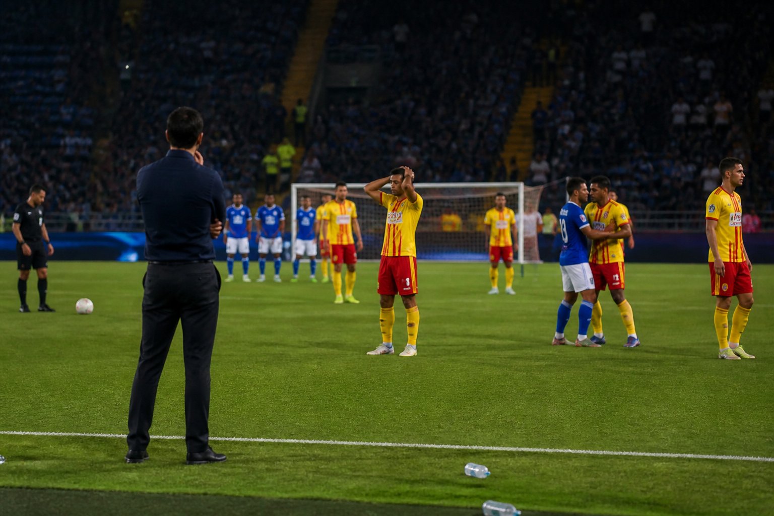 Jugadores de Junior muestran frustración mientras Millonarios mantiene una defensa organizada en un estadio de fútbol.